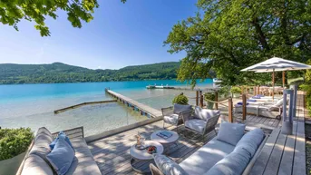 Geräumige Holzterrasse mit bequemen Lounge-Möbeln und direktem Blick auf den See und den privaten Steg.