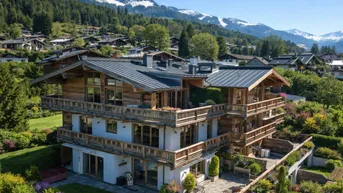 Großes Chalet mit mehreren Balkonen und Terrassen, umgeben von einem gepflegten Garten und mit Bergblick.