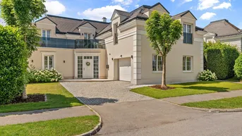 Elegante Villa mit gepflegtem Vorgarten, gepflasterter Auffahrt und integrierter Garage.