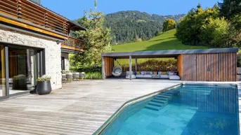 Großzügige Holzterrasse mit Pool, überdachtem Loungebereich und herrlichem Bergblick.