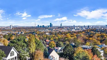 Panoramablick über die Stadt mit herbstlicher Baumlandschaft und Fernsicht auf Hochhäuser.