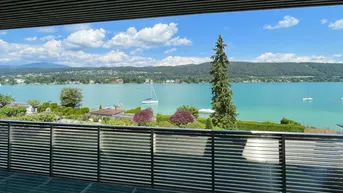 Panoramablick vom Balkon auf den glitzernden See und die umliegende Natur unter strahlend blauem Himmel.