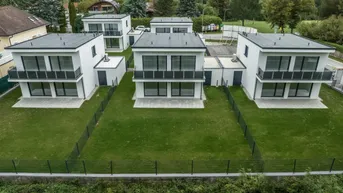 Moderne Reihenhäuser mit Flachdächern und privaten Gärten in einer Wohnsiedlung.