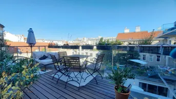 Sonnige Dachterrasse mit Holzboden, Sitzgelegenheiten und Blick über die Stadt.