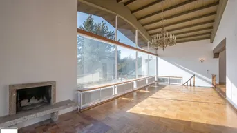 Geräumiges Wohnzimmer mit hohen Holzdecken, Parkettboden und Panoramafenstern.
