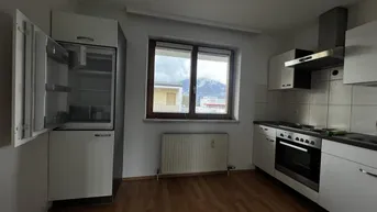 Einfache Küche mit Einbauschränken, Kühlschrank und Herd, mit Blick auf die Berge.