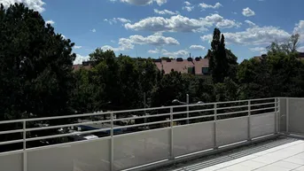 Geräumige Terrasse mit hellen Fliesen und Blick auf die grüne Umgebung unter blauem Himmel.