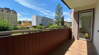 Heller Balkon mit braunem Sichtschutz und Blick auf die umliegenden Gebäude und Bäume.