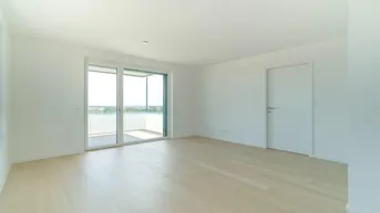 Helles, leeres Zimmer mit hellem Holzboden und Zugang zu einem Balkon, ideal als Wohnbereich.