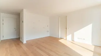 Heller, leerer Raum mit Parkettboden und weißen Wänden, durchflutet von natürlichem Licht.