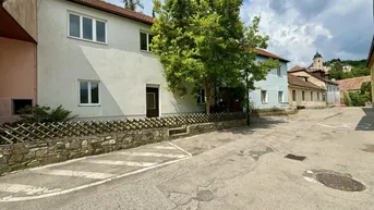 Traditionelles Gebäude in einer ländlichen Umgebung mit Blick auf eine Kirche im Hintergrund.