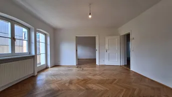 Helles, leeres Zimmer mit klassischem Fischgrätparkett und hohen Decken, bereit zur individuellen Gestaltung.