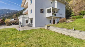 Weißes Wohnhaus mit Gartenbereich, Terrasse und Blick auf die umliegende Berglandschaft.