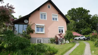 Rosa verputztes Einfamilienhaus mit Satteldach, Vorgarten und gepflasterter Auffahrt.