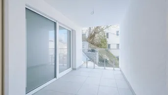 Heller Balkon mit Fliesenboden und Glasgeländer, ideal für entspannte Stunden im Freien.