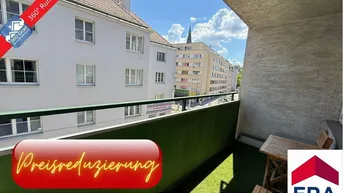 Heller Balkon mit Kunstrasen, kleinem Holztisch und Blick auf die umliegenden Gebäude und die Stadt.
