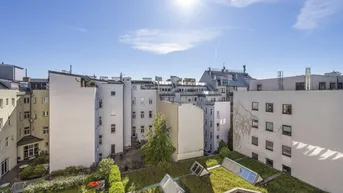 Sonnenverwöhnter Blick auf den begrünten Innenhof mit Dachgärten und umliegenden Gebäuden.