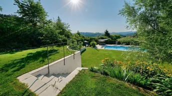 Weitläufiger Garten mit Treppen, Rasenflächen und Fernblick auf die umliegende Hügellandschaft und den Pool.