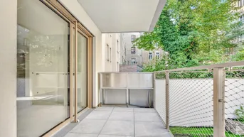 Heller Balkon mit Fliesenboden und modernem Metallgeländer, bietet Blick auf umliegende Gebäude und Grünflächen.