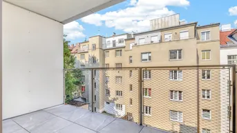 Moderner Balkon mit Fliesenboden und Metallgeländer, bietet Blick auf umliegende Gebäude.