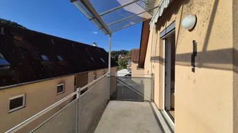 Heller Balkon mit Glasüberdachung und Metallgeländer, bietet einen Blick auf die Umgebung.