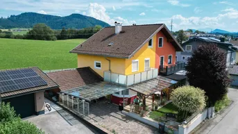 Luftaufnahme eines Einfamilienhauses mit Solaranlage, Carport und Garten in ländlicher Umgebung.