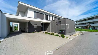 Moderne Doppelhaushälfte mit Carport und gepflasterter Einfahrt in einer Wohnsiedlung.