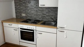 Kleine Küche mit Dachschräge, Holztheke und integrierten Geräten in gutem Zustand.