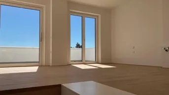 Helles, leeres Zimmer mit Holzboden und großen Schiebetüren zu einer Terrasse.