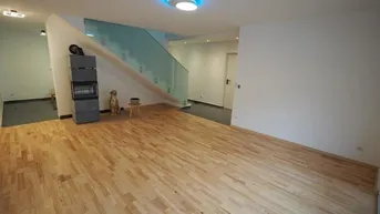 Geräumiges Wohnzimmer mit hellem Parkettboden, modernem Kaminofen und eleganter Glastreppe.