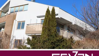 Moderne Wohnanlage mit weißer Fassade, Holzverkleidung und Balkonen unter blauem Himmel.
