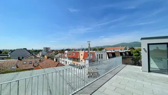 Sonnige Dachterrasse mit Fliesenboden und freiem Blick auf die Stadt und Berge.