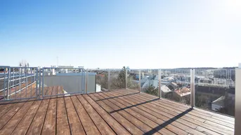 Geräumige Dachterrasse mit Holzboden und weitem Blick über die Stadt.