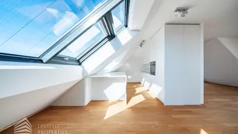 Helle Dachgeschosswohnung mit moderner Einbauküche, Holzboden und großen Dachfenstern.