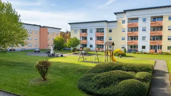 Mehrere Mehrfamilienhäuser mit großem Gemeinschaftsgarten und Kinderspielplatz.