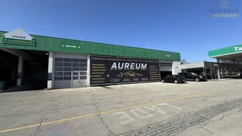 Außenansicht eines Reifencenters mit großem Werbebanner und Parkplatz unter blauem Himmel.
