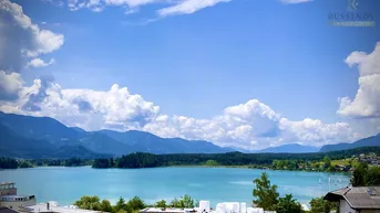 Atemberaubender Blick auf einen blauen See, umgeben von majestätischen Bergen unter einem weiten Himmel.