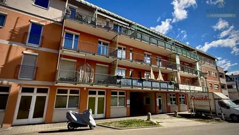 Mehrstöckiges Wohngebäude mit Balkonen und orangefarbener Fassade unter blauem Himmel.