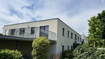 Modernes Mehrfamilienhaus mit Balkonen und gepflegter Außenanlage unter blauem Himmel.