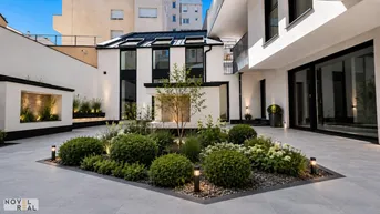 Innenhof mit gepflegter Gartenanlage, modernen Pflanzen und Beleuchtung, umgeben von Gebäudefassaden.