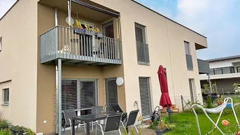 Modernes Reihenhaus mit Balkon, möblierter Terrasse und kleinem Gartenbereich.