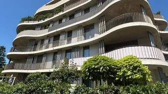 Moderne Wohnanlage mit geschwungenen Balkonen und üppiger Bepflanzung.