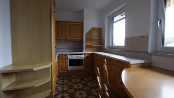 Küche mit Holzschränken, gemustertem Fliesenboden und einem integrierten Backofen.