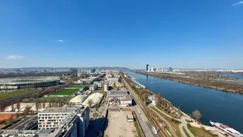 Panoramablick über die Donau, die Stadt Wien und das Ernst-Happel-Stadion unter blauem Himmel.