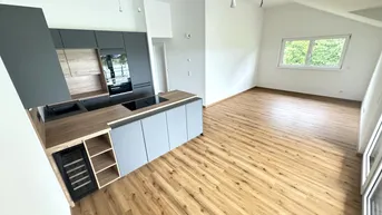 Moderne offene Küche mit Holzarbeitsplatte, grauen Fronten und Blick ins Grüne.