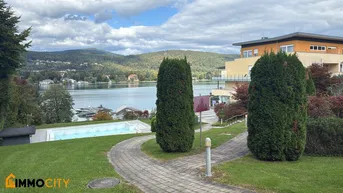 Gepflegter Gartenbereich mit Pool und Seeblick, umgeben von Bergen und einem modernen Gebäude.