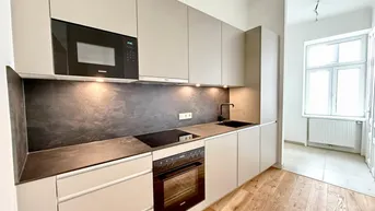 Moderne Einbauküche mit hellen Fronten, integrierten Geräten und Holzboden.