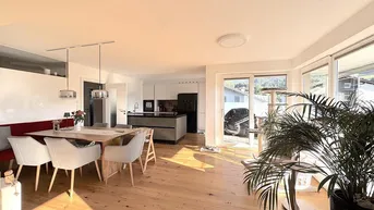 Lichtdurchfluteter offener Wohnbereich mit Küche, Essbereich und Zugang zum Balkon.