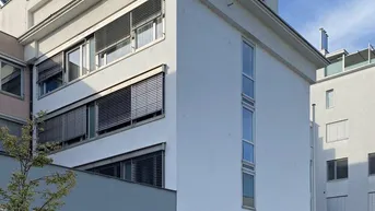 Modernes Mehrfamilienhaus mit weißer Fassade, vielen Fenstern und Außenjalousien.