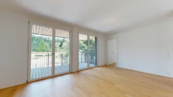 Helles Zimmer mit Holzboden und Zugang zu einem Balkon mit Blick ins Grüne.